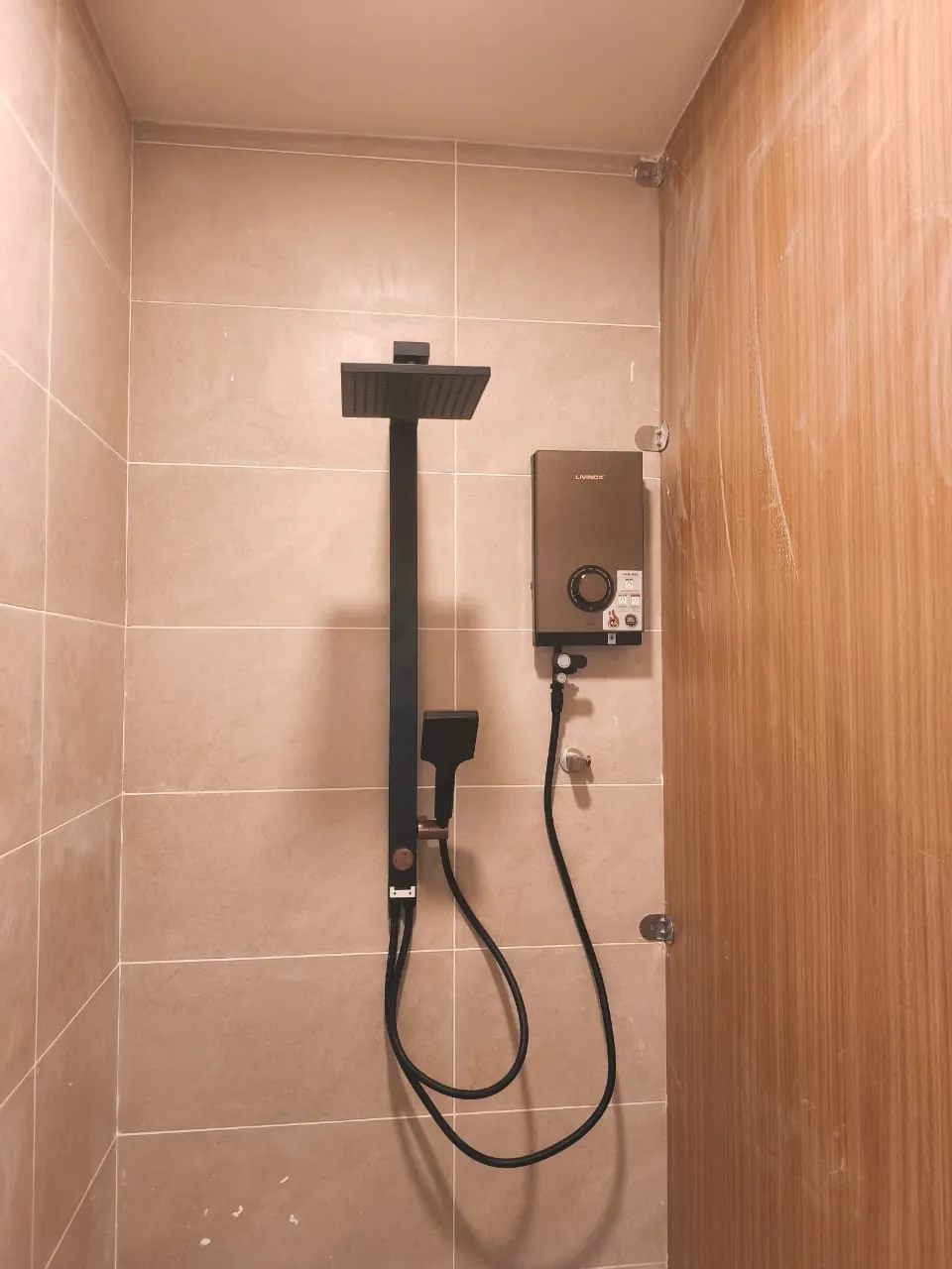 Renovix Home Services 在吉隆坡瓷砖卫浴墙面上安装的黑色花洒立柱与速热热水器。