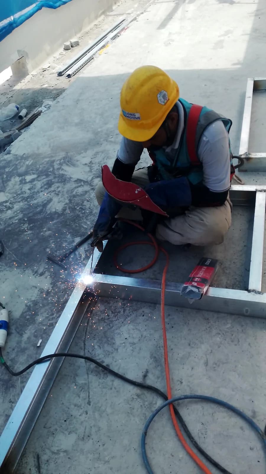 焊工在混凝土楼板上焊接金属框架,属 Renovix Home Services 的现场金属工程。