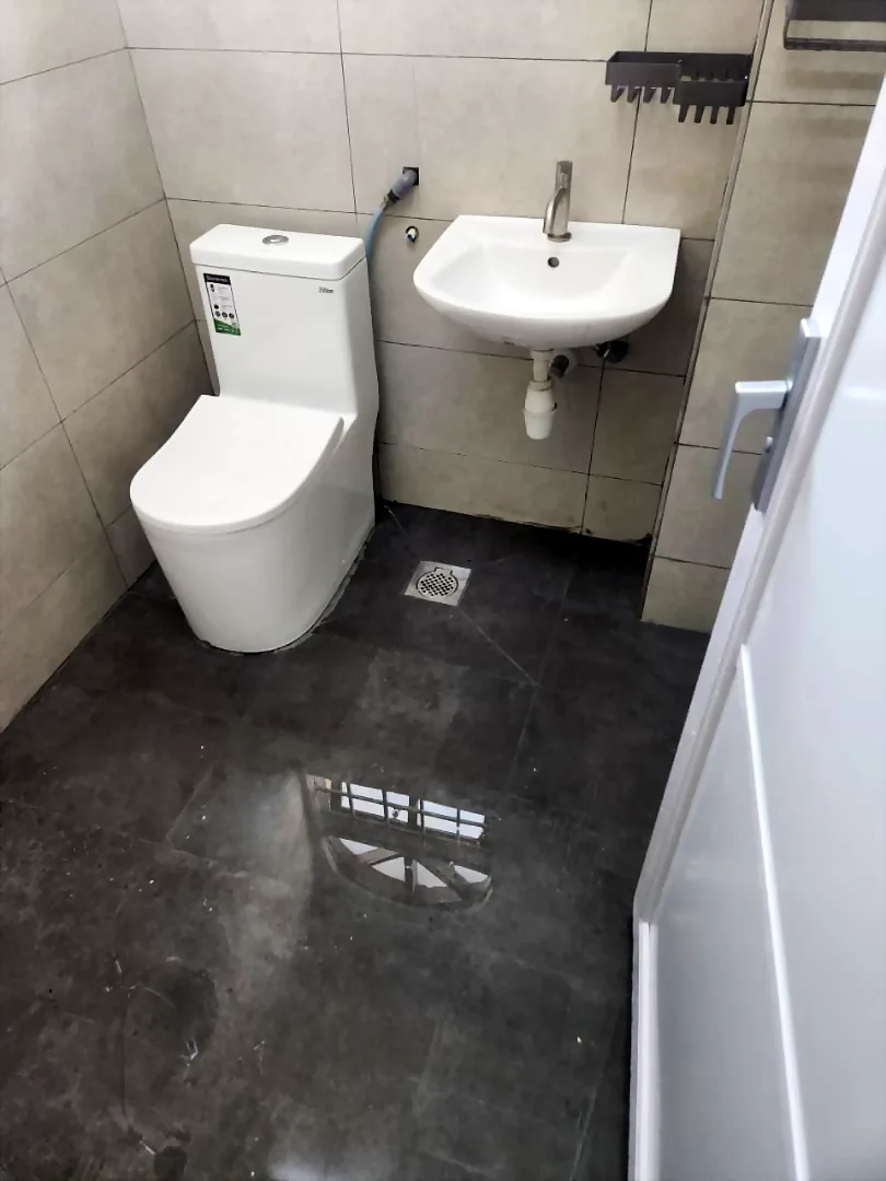 Renovix Home Services 在吉隆坡铺砖浴室内安装的马桶与壁挂洗手盆。