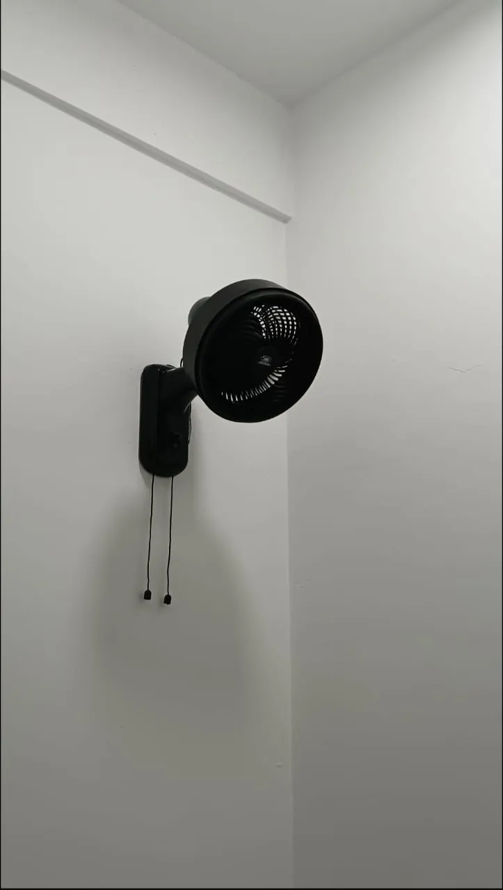 Black wall-mounted fan with pull cords fixed on a white wall by Renovix Home Services in Kuala Lumpur.